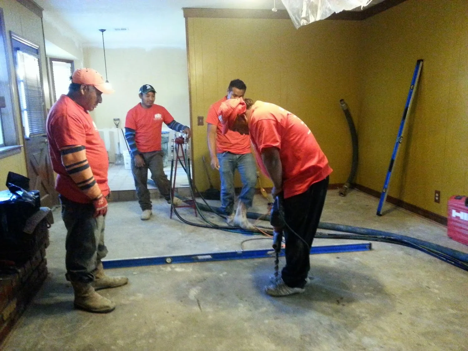 Foundation repair crew working on concrete floor with moisture treatment equipment in commercial space