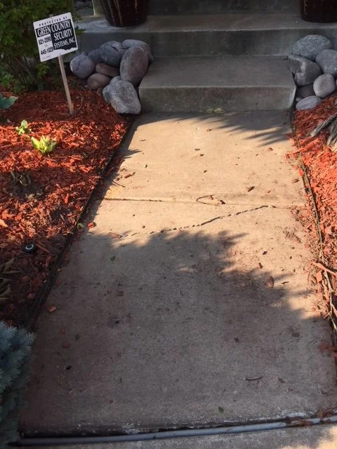 Concrete entryway with red mulch borders and river rock accents flanking steps