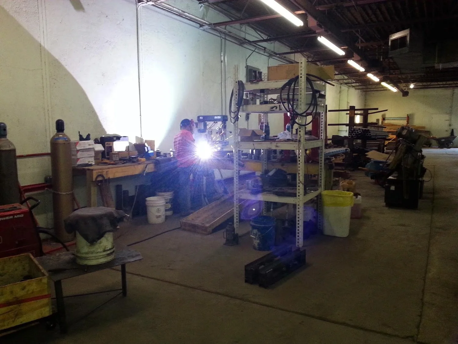 Welder performing MIG welding on structural steel frame in industrial workshop