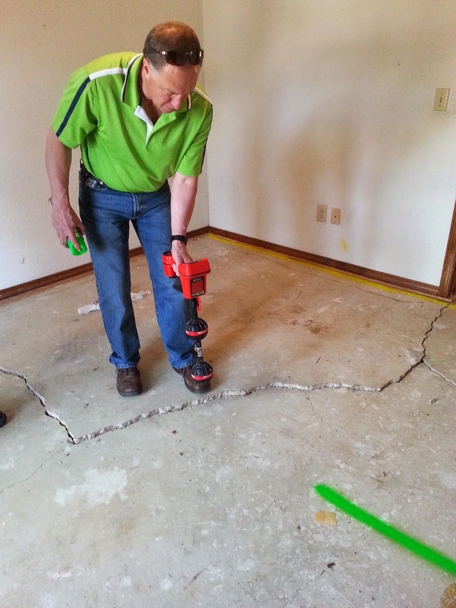 Technician inspecting concrete foundation crack with diagnostic tool in residential basement