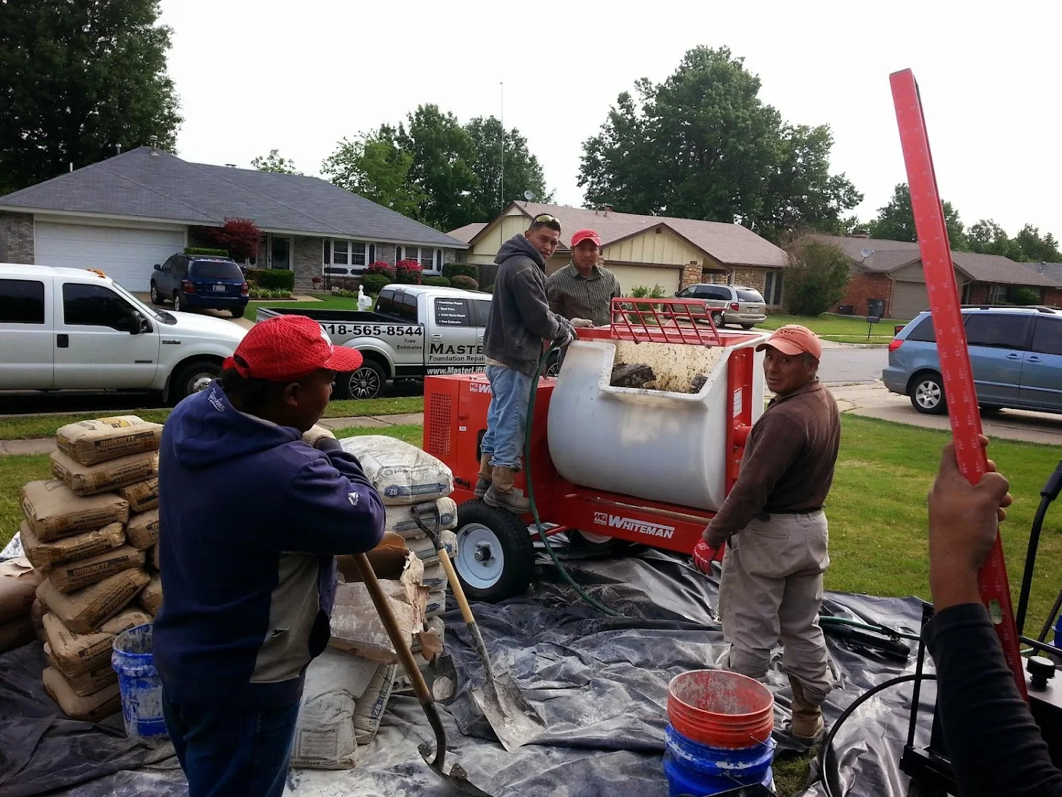 Foundation repair crew operating concrete mixer equipment during residential project in Tulsa